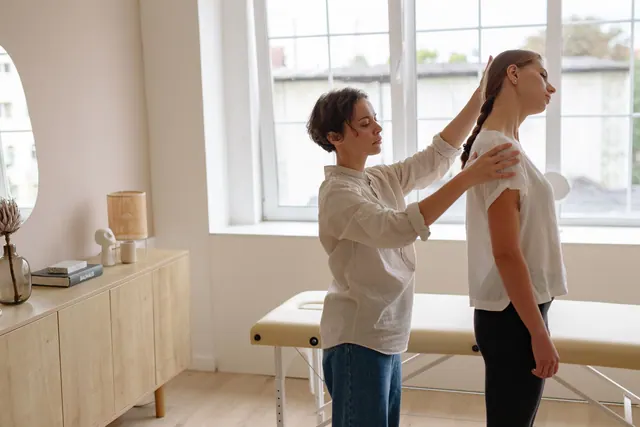 A chiropractor adjusts a patient's posture in a well-lit clinic room. Chiropractic practice pricing and profit guide for 2027