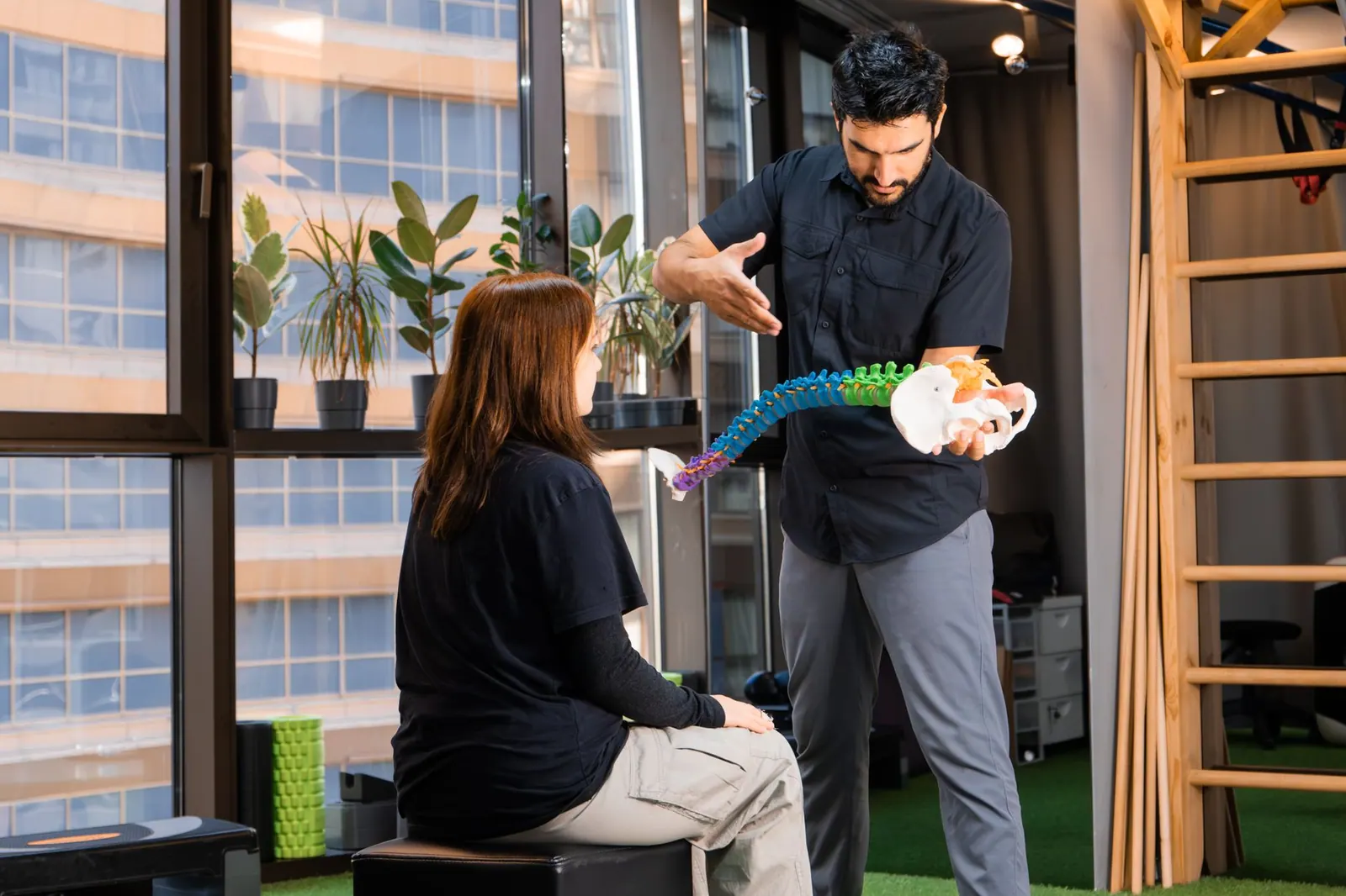 Chiropractor demonstrating spine anatomy to a patient during consultation indoors. Chiropractic practice software and KPI guide for 2027