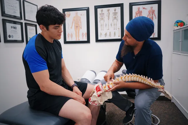 A doctor explains spinal issues to a patient using a spine model during a medical consultation. How to assess chiropractic practice software